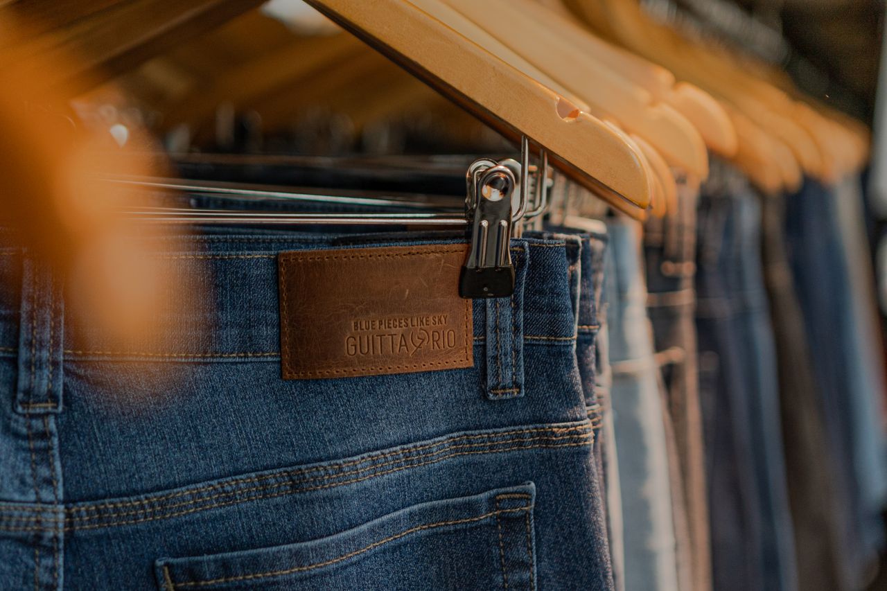 Stylish close-up of denim jeans displayed on wooden hangers, ideal for fashion concepts.